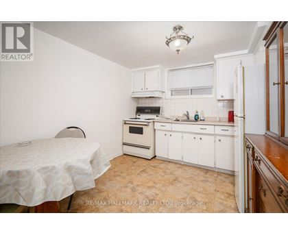 A kitchen with white cabinets and a table with a white tablecloth.