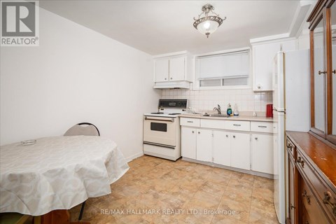 A kitchen with white cabinets and a table with a white tablecloth.