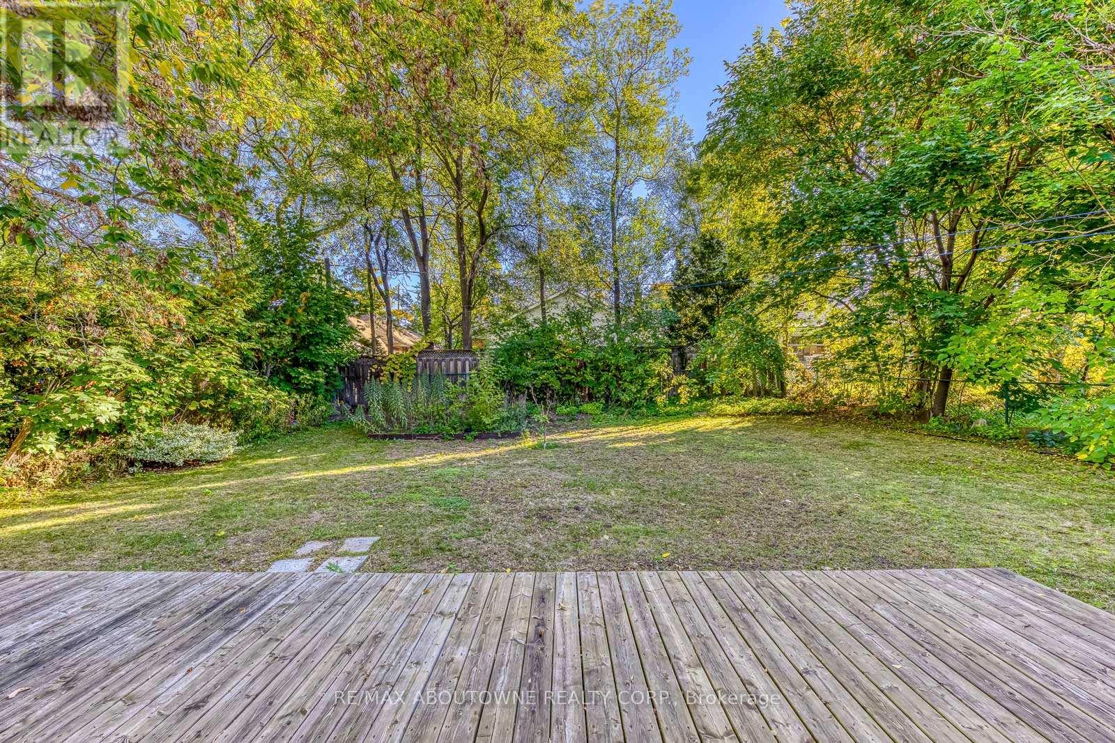 A wooden deck overlooks a grassy area with trees in the background.