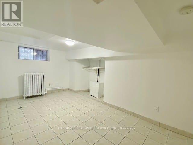 A spacious room with white walls and a radiator on the floor.