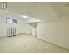 A spacious room with white walls and a radiator on the floor.