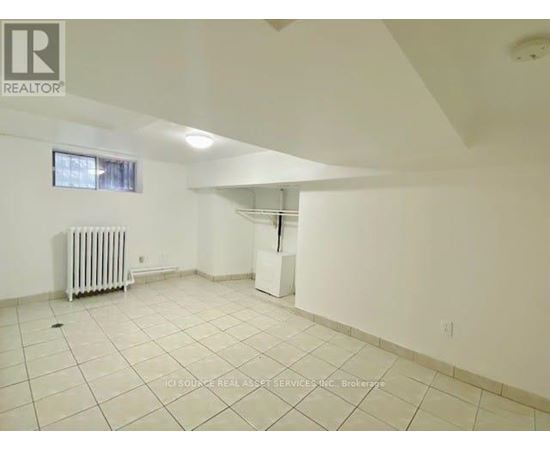 A spacious room with white walls and a radiator on the floor.