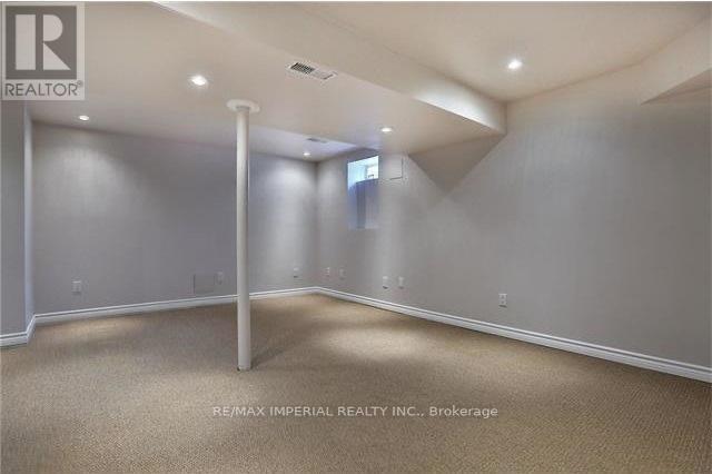 A spacious room with beige carpeting and white walls, with a door on the left side.