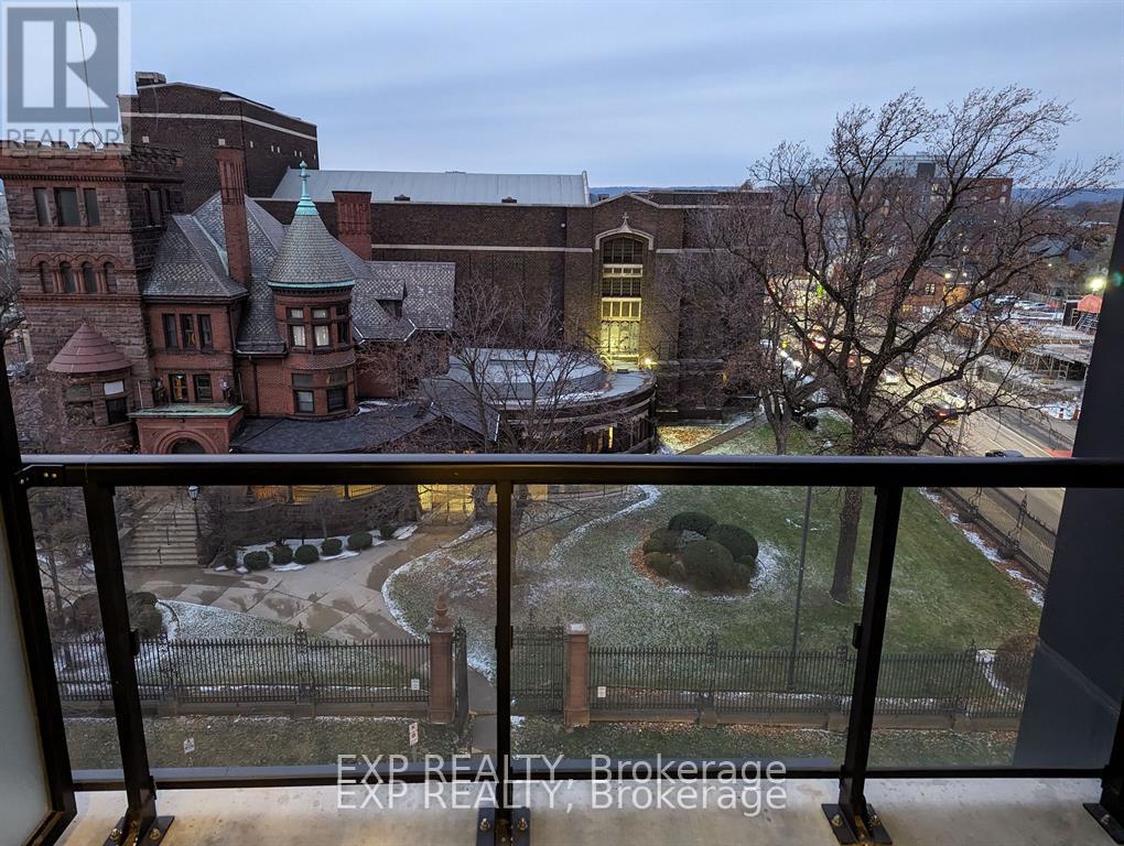 A view from a balcony overlooking a courtyard with a fountain and a building in the background.