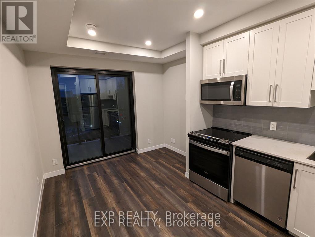 A kitchen with white cabinets and a black fridge.