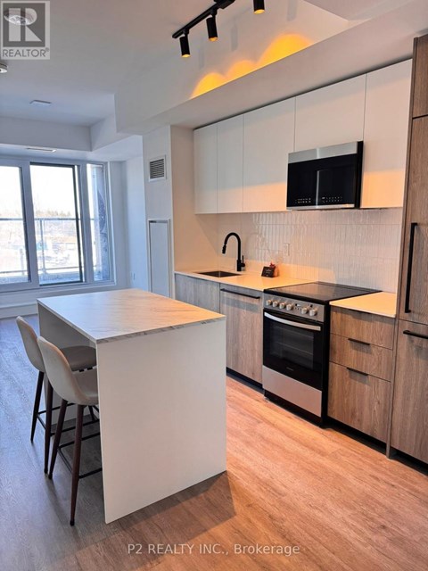 A modern kitchen with wooden cabinets and a flat screen TV mounted above the stove.