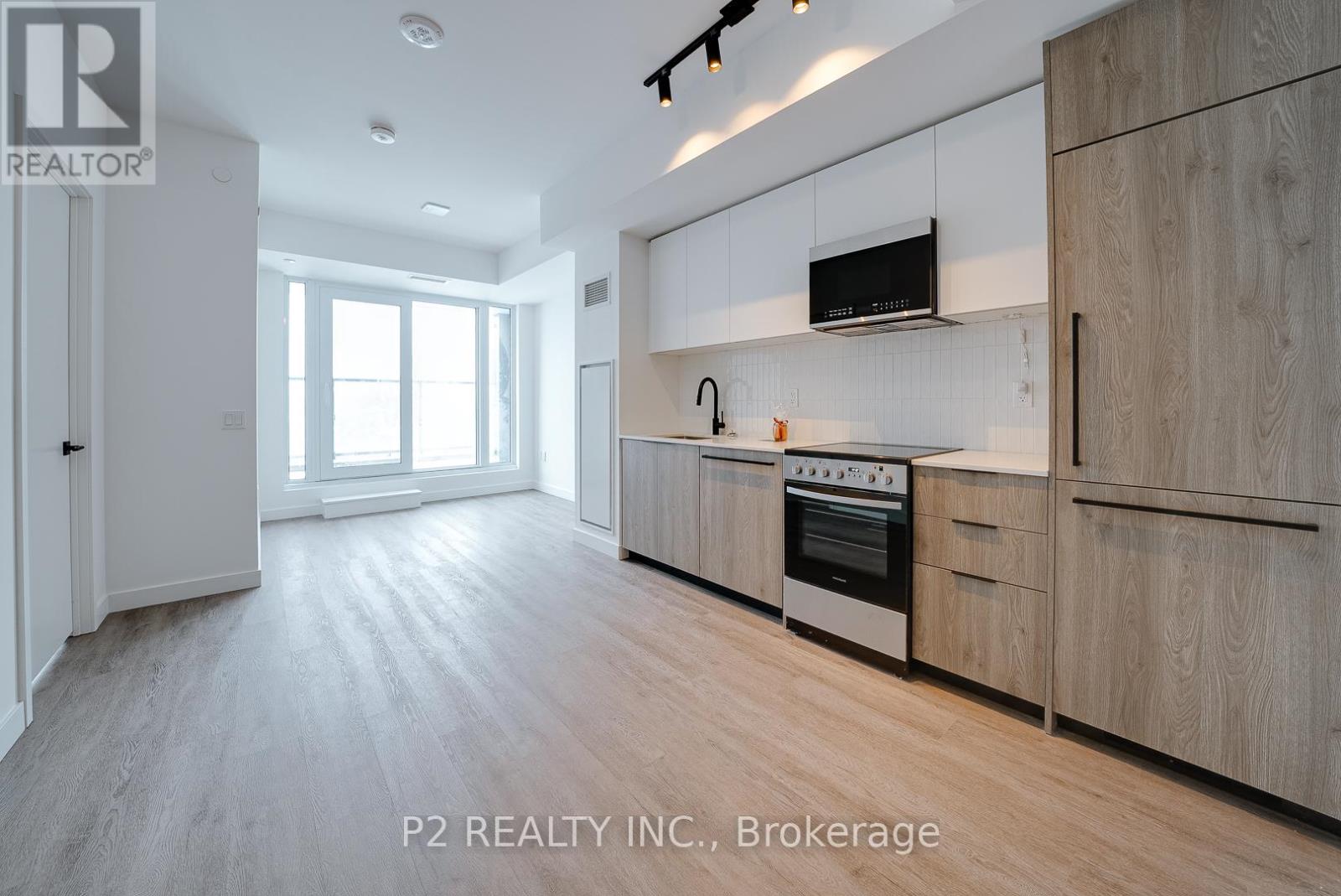 A modern kitchen with wooden cabinets and a flat screen TV mounted above the stove.