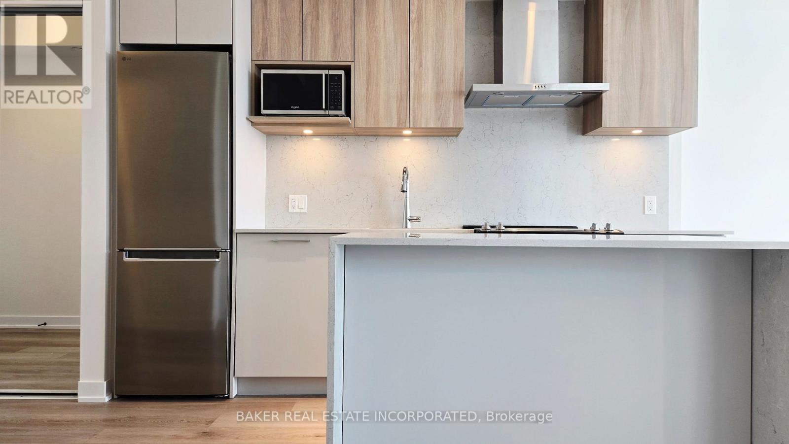 A modern kitchen with a stainless steel refrigerator and a stove top oven.