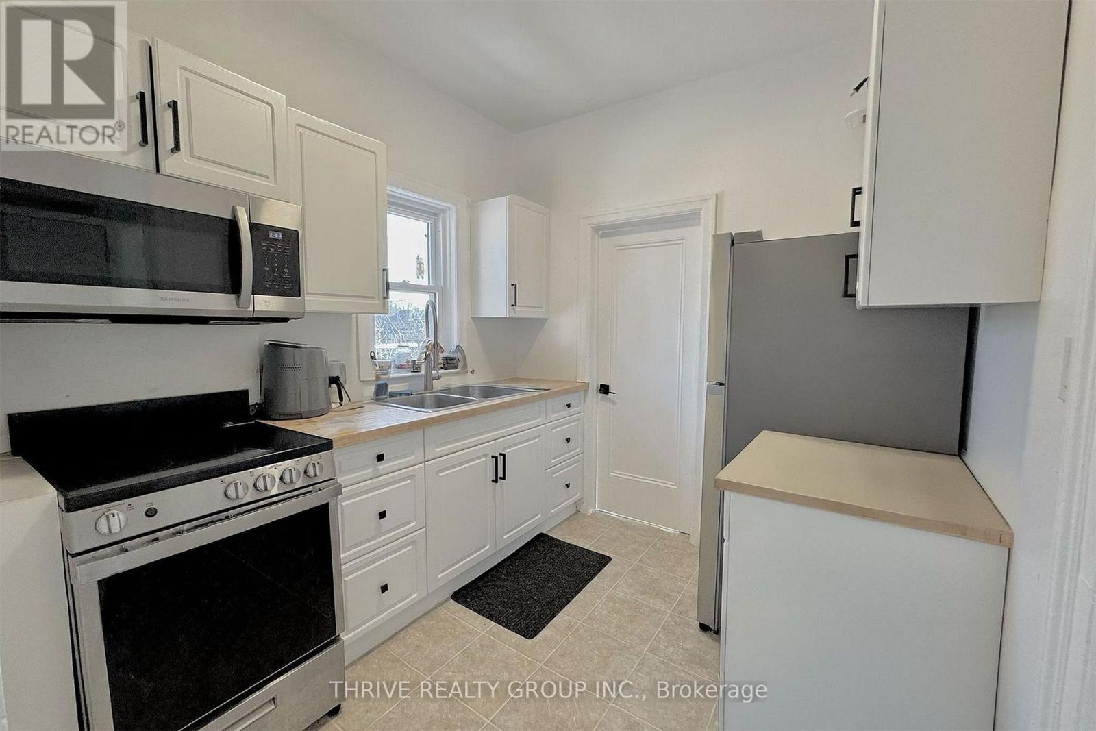 A kitchen with white cabinets and appliances is on the market with Thrive Realty Group, Inc.