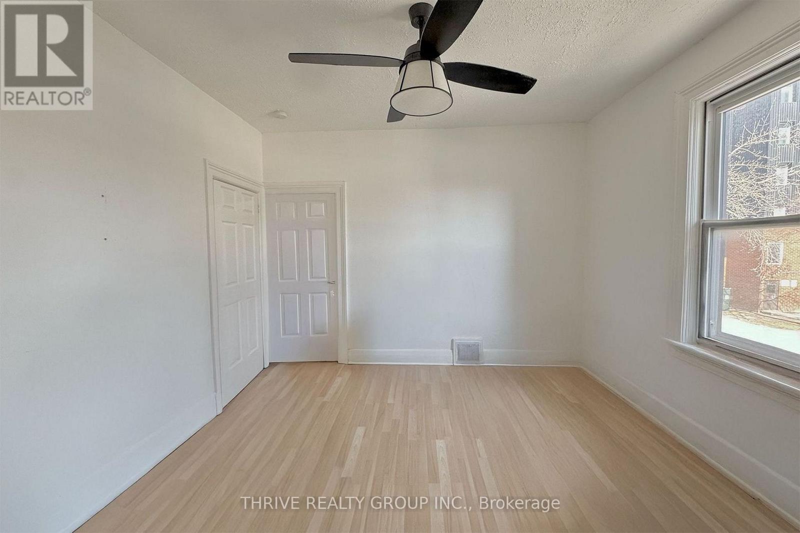 A room with a ceiling fan and a window with a view of a building outside.