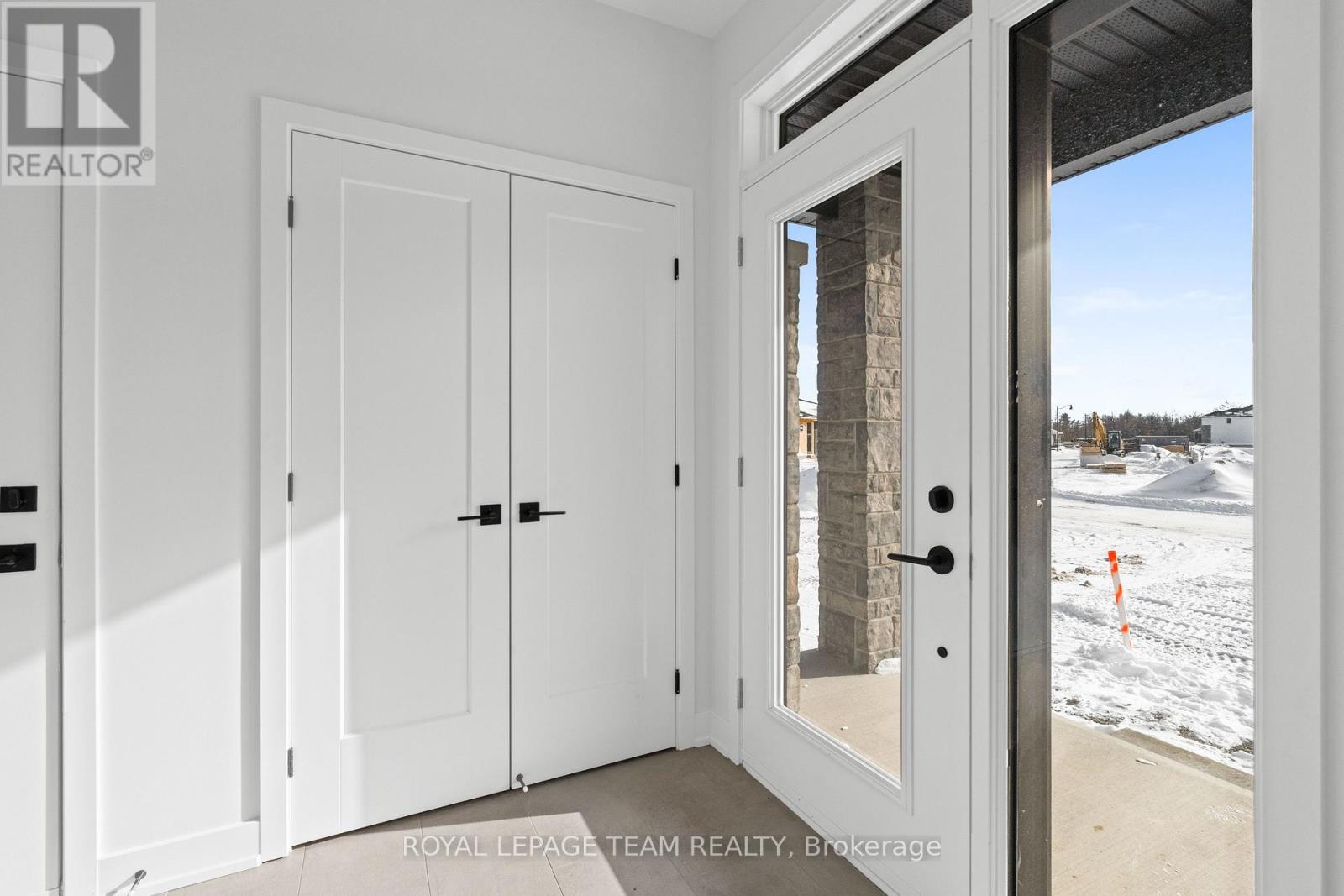 A white door with a glass window is open to a snowy landscape.
