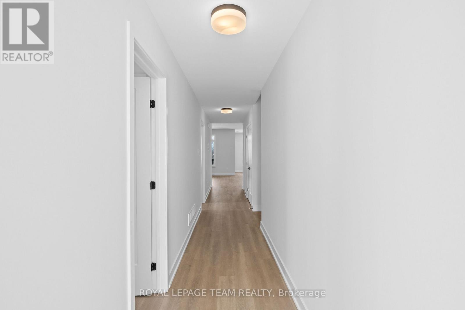 A long hallway with a light on the ceiling and doors on the left.
