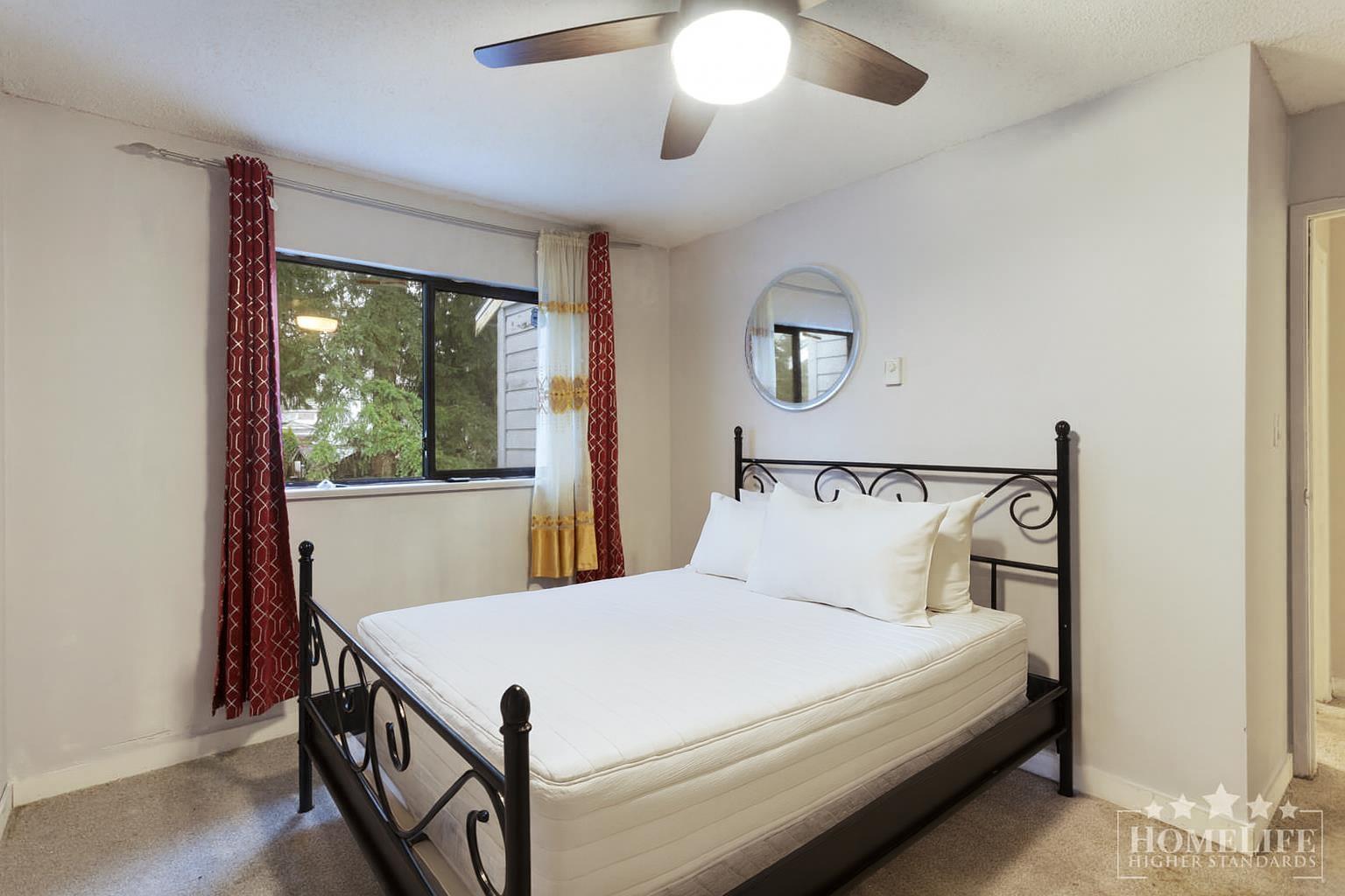 A bedroom with a bed, window, and a ceiling fan.