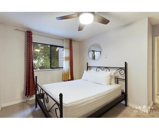 A bedroom with a bed, window, and a ceiling fan.