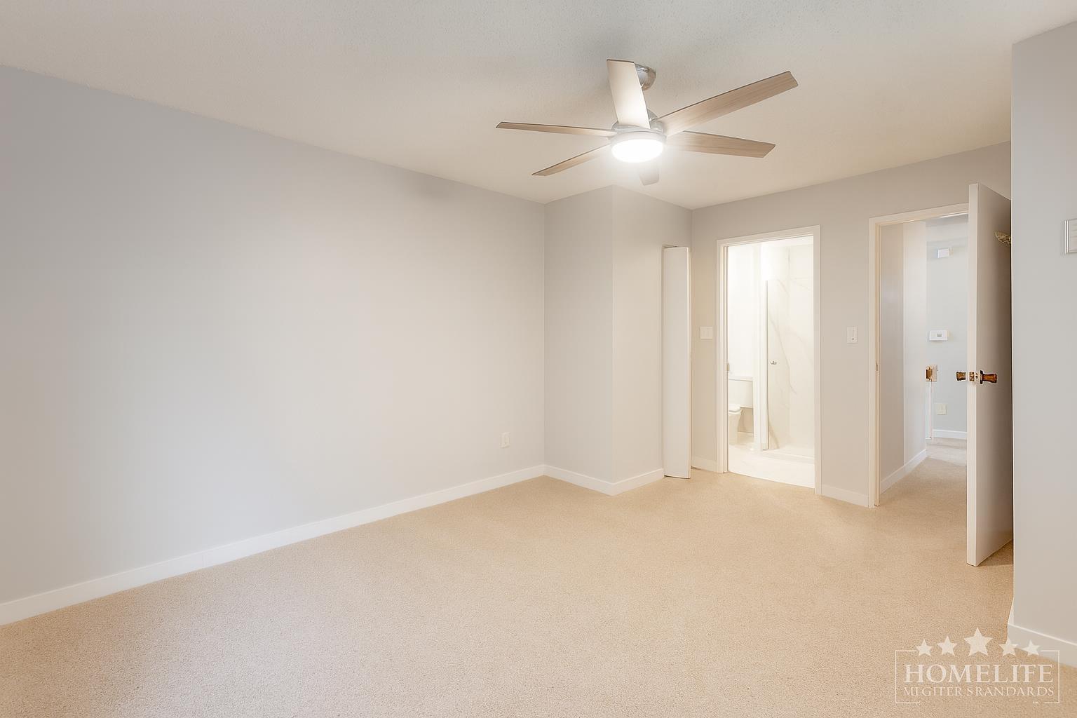 A spacious room with a ceiling fan and carpeted floor.