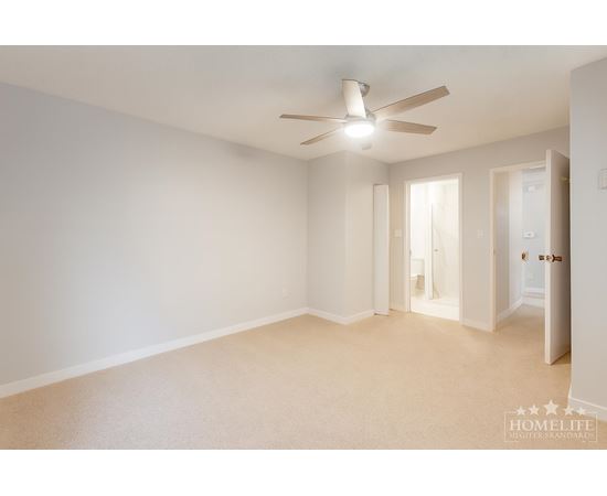 A spacious room with a ceiling fan and carpeted floor.