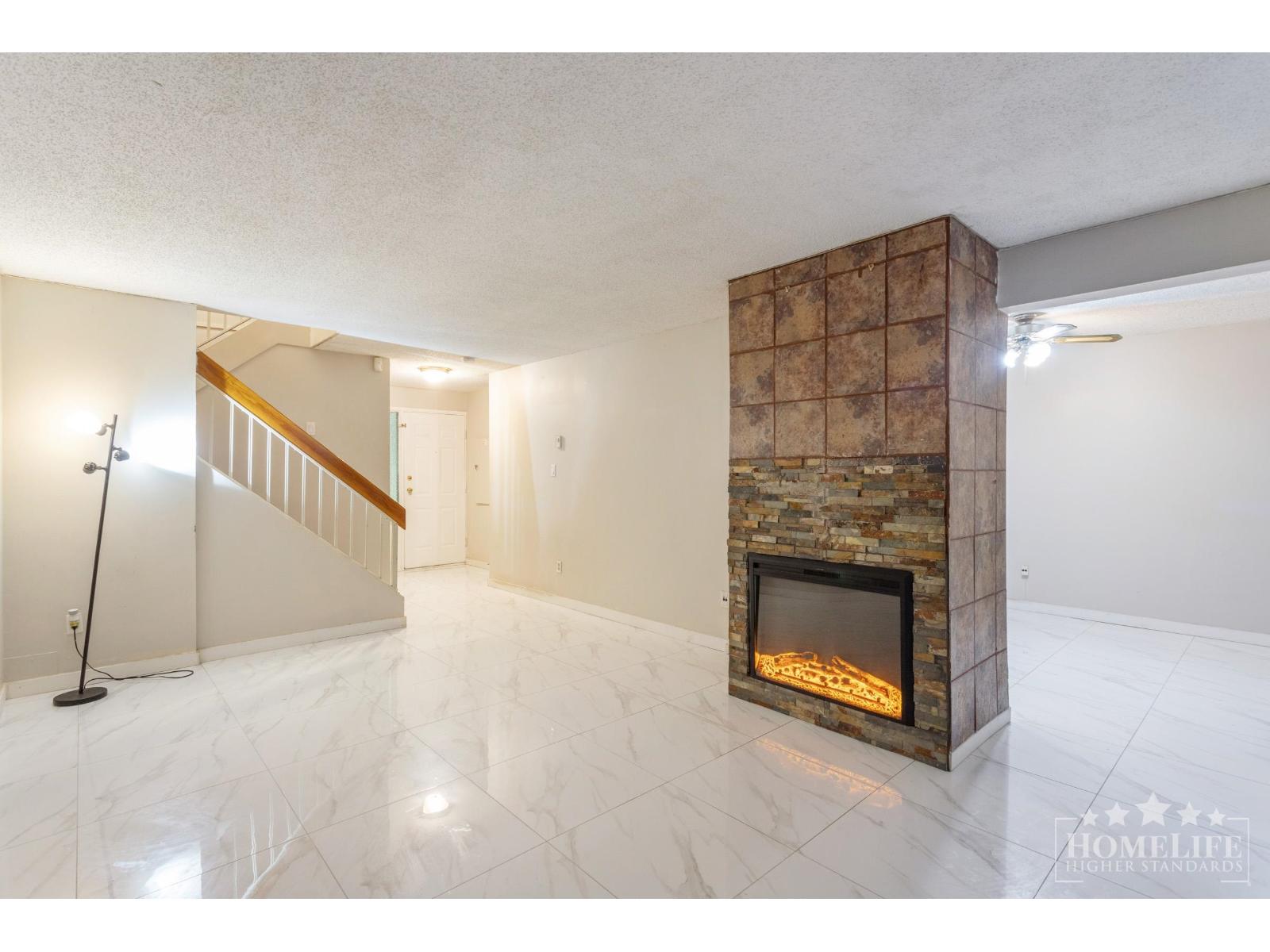 A living room with a stone fireplace and a marble floor.