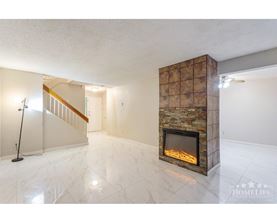 A living room with a stone fireplace and a marble floor.