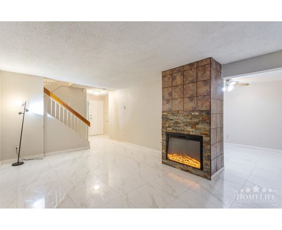 A living room with a stone fireplace and a marble floor.