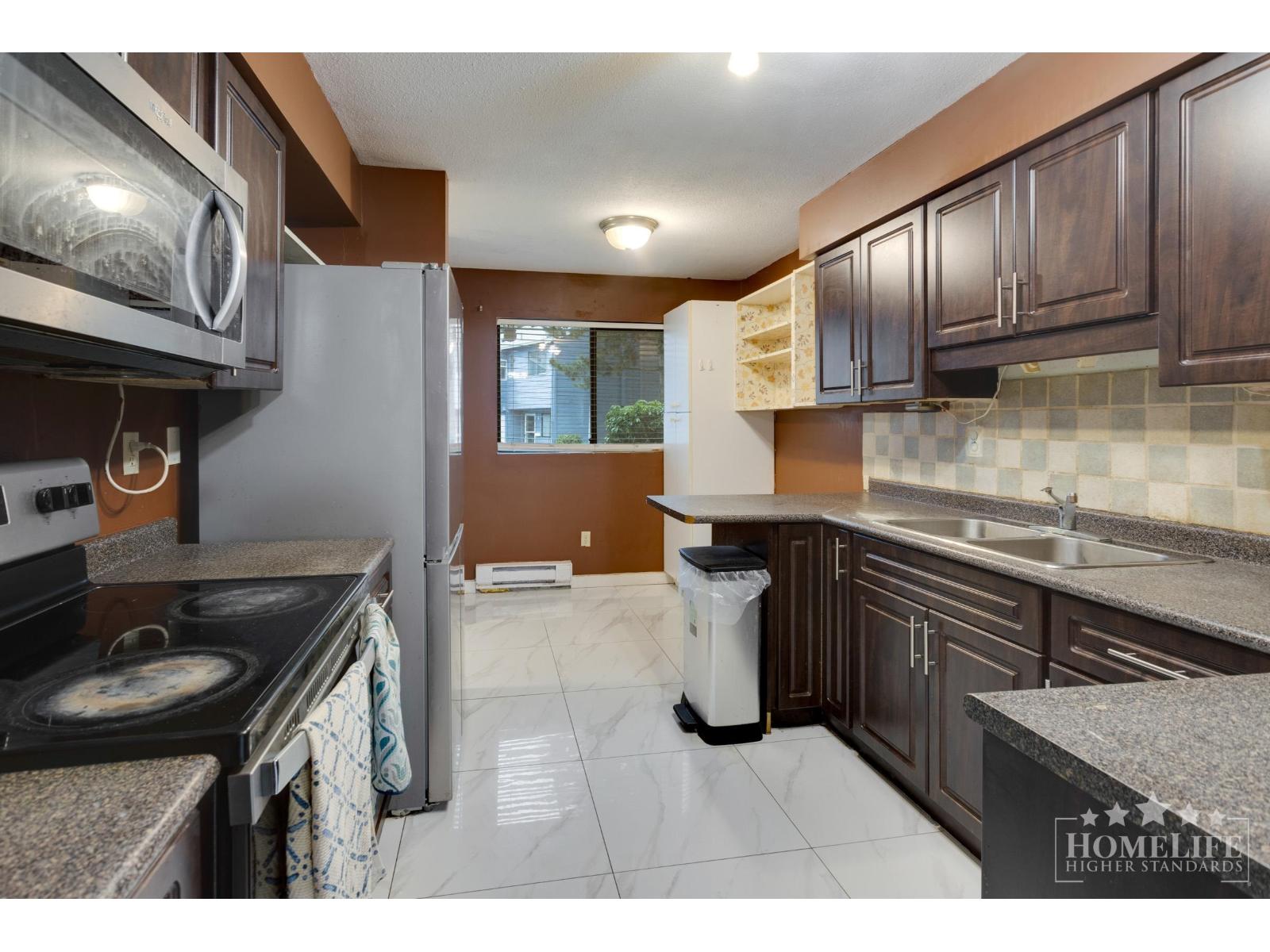 A kitchen with a stove top oven and a refrigerator.