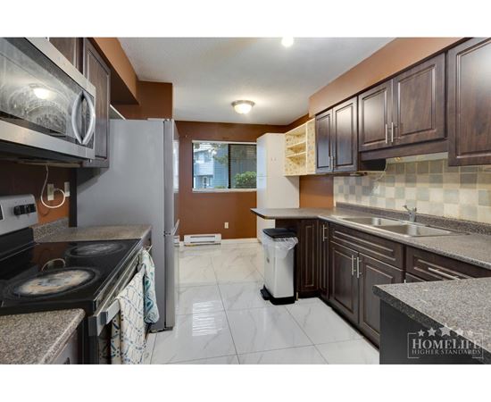 A kitchen with a stove top oven and a refrigerator.