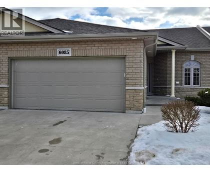A house with a garage door and a sign that says "6085".