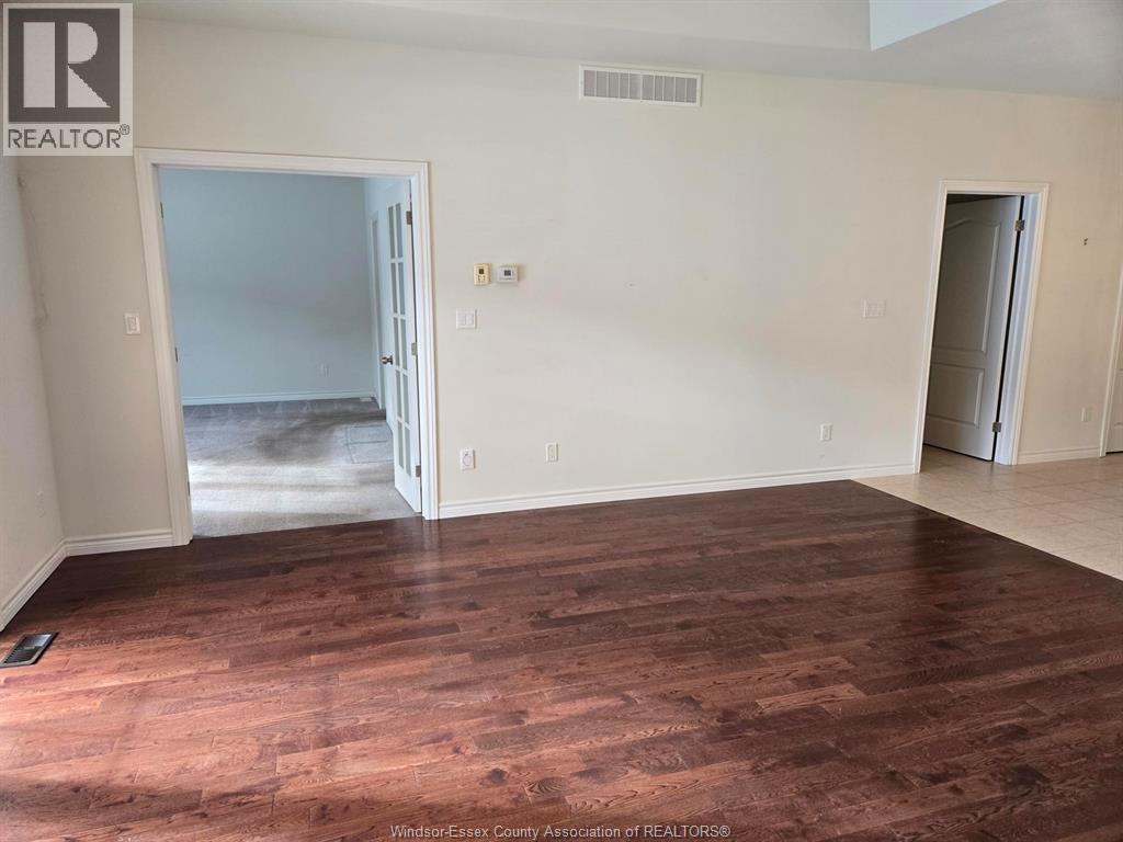 A room with wooden floors and white walls, with a doorway leading to another room.