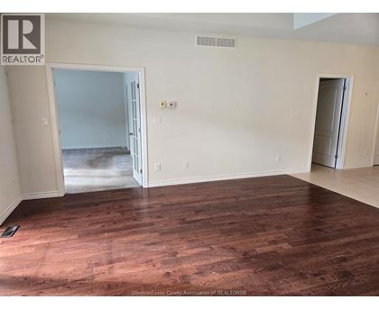 A room with wooden floors and white walls, with a doorway leading to another room.