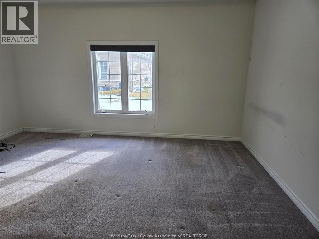 A room with a carpeted floor and a window showing a view of a building outside.