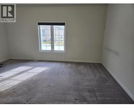 A room with a carpeted floor and a window showing a view of a building outside.