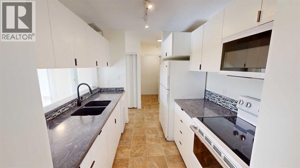 A kitchen with white cabinets and a black countertop.
