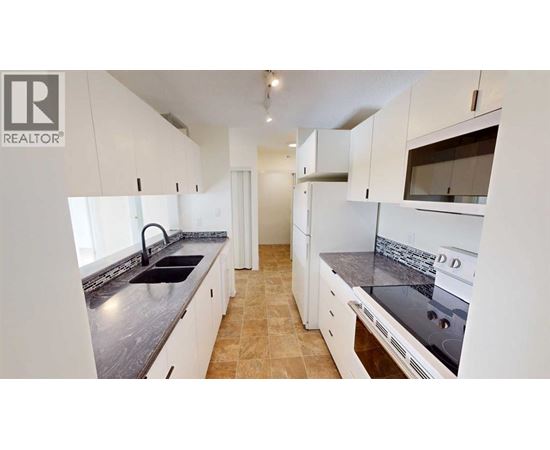 A kitchen with white cabinets and a black countertop.
