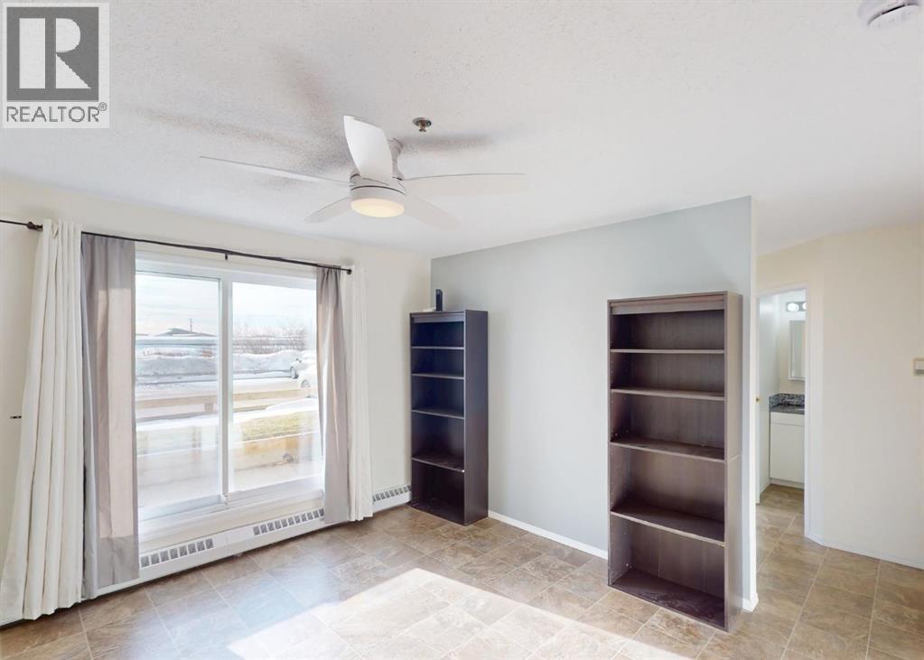 A room with a sliding glass door, a ceiling fan, and a built-in shelf unit.