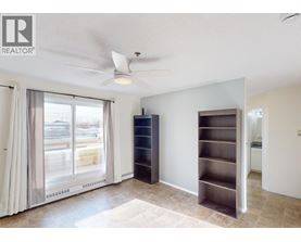 A room with a sliding glass door, a ceiling fan, and a built-in shelf unit.