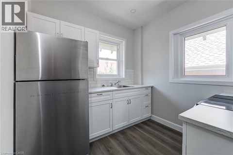 A kitchen with a stainless steel refrigerator and white cabinets.