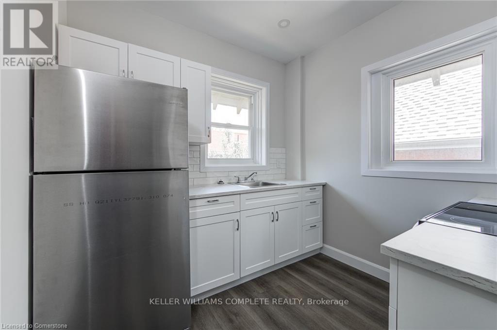 A kitchen with a stainless steel refrigerator and white cabinets.
