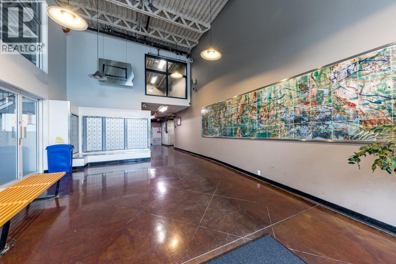 A large, colorful map is displayed on the wall in a spacious room with wooden floors and a blue trash can.