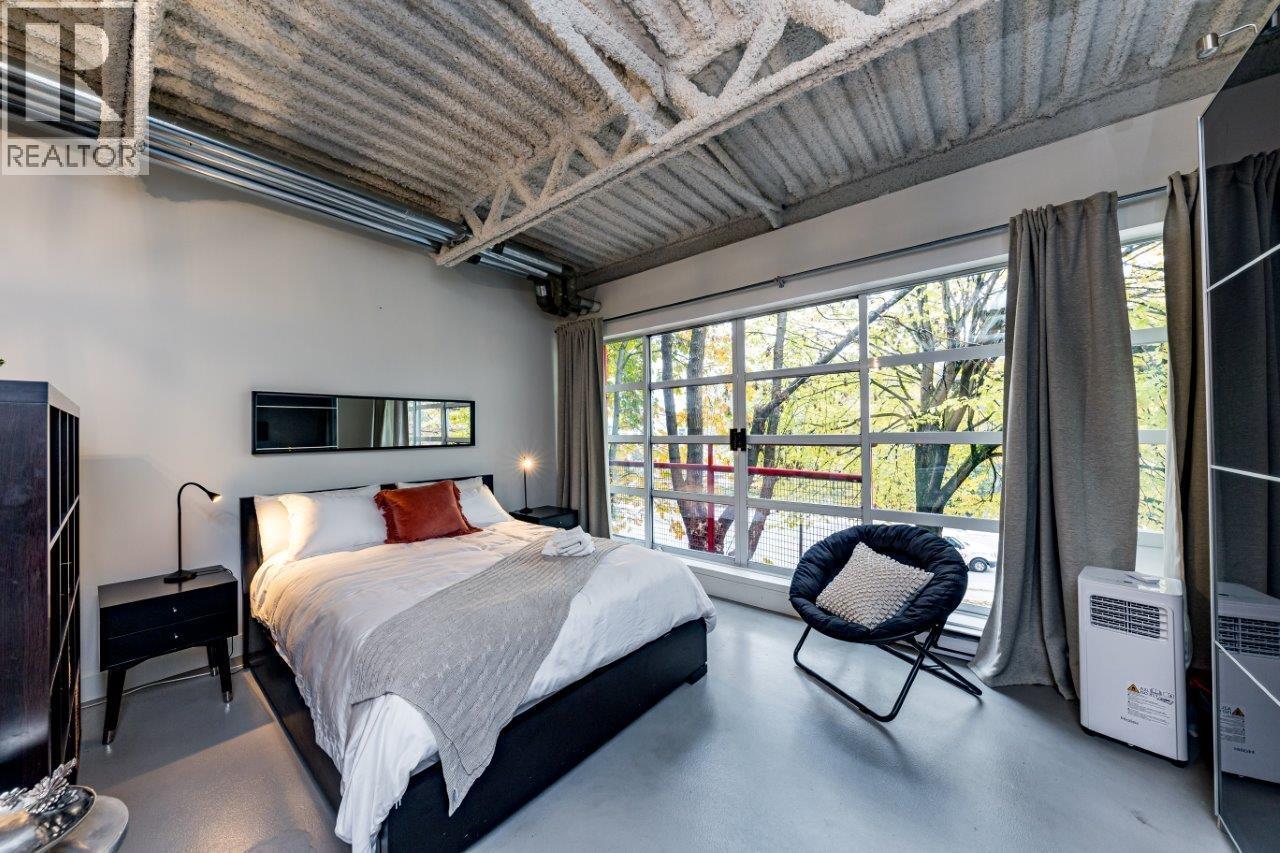 A bedroom with a large bed and a chair by the window.