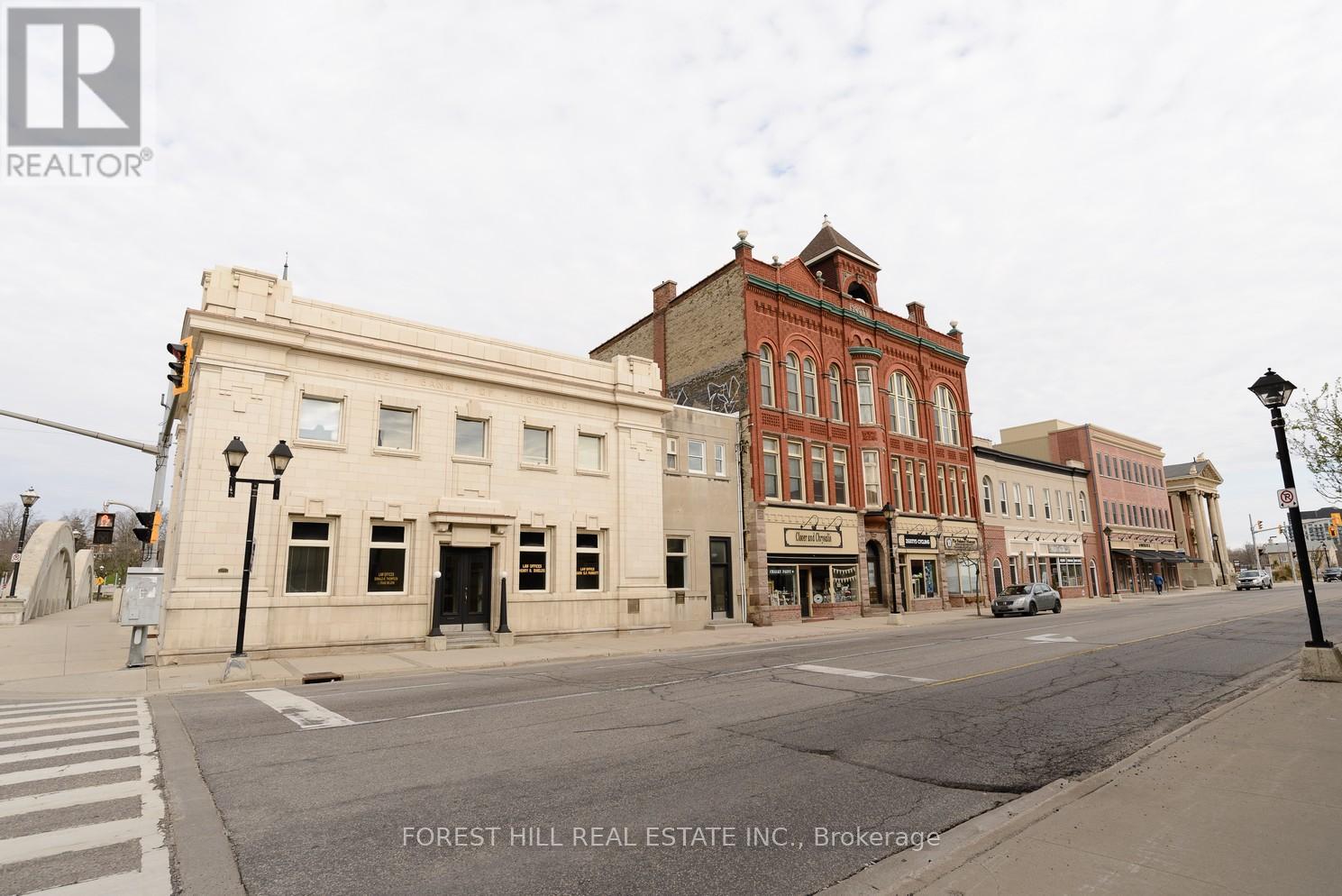A street view of a town with a building that says Forest Hill Real Estate Inc. Brokerage.