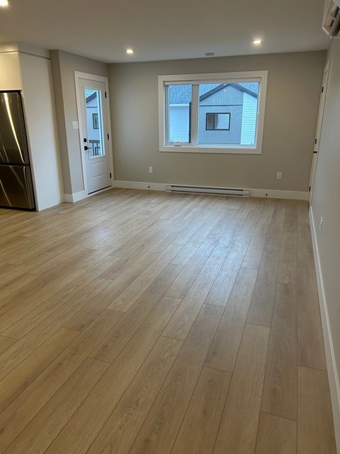 A room with wooden flooring and a window.