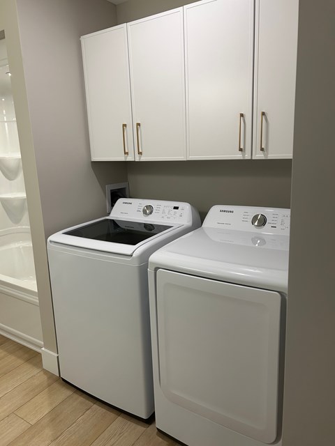 Two white front loading washing machines in a laundry room.