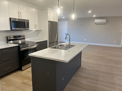 A kitchen with a white countertop and black cabinets.