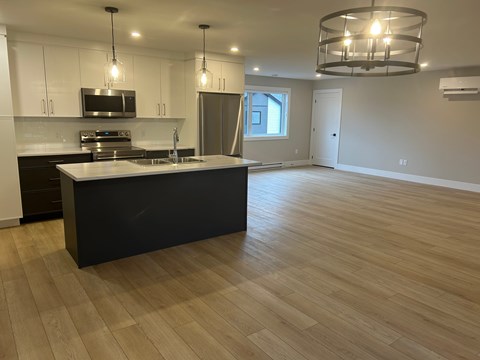 A kitchen with a black island and wooden floors.