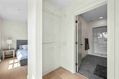 A bedroom with a bed, nightstand, and a bathroom with a shower.