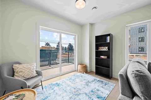 A living room with a grey sofa, a black bookshelf, and a blue rug.
