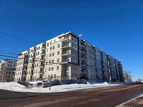 A large apartment building with a parking lot in front.
