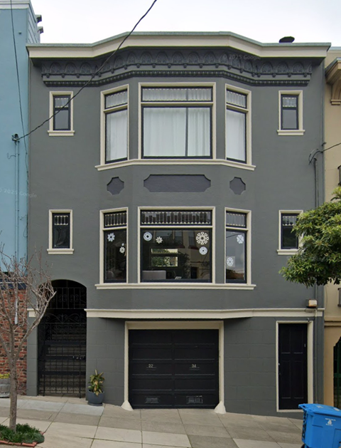 A grey two-story building with a black garage door.