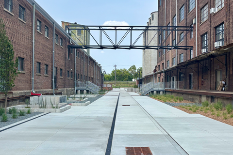 A long, empty walkway between two rows of brick buildings.
