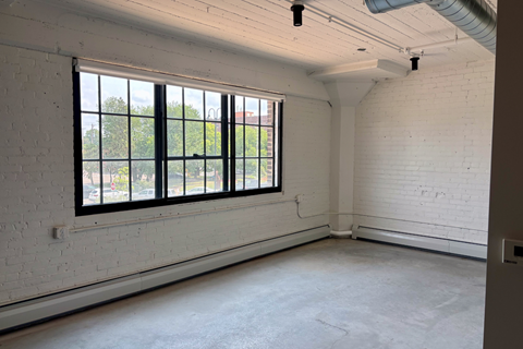 A white room with a large window and a white brick wall.