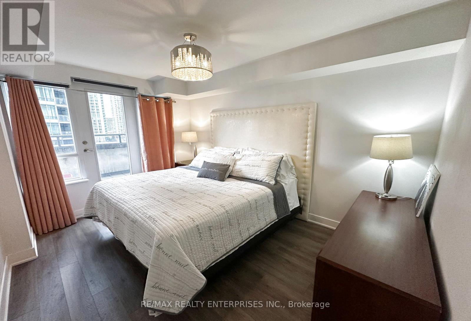 A bedroom with a large bed and a chandelier.